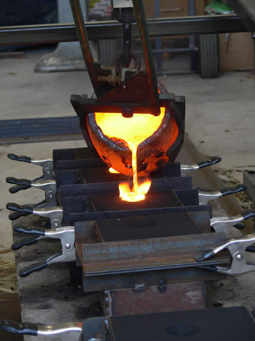 Pouring molten bronze into the sand molds